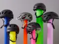 Sechs Helme, die den Unterschied zwischen Reithelm und Fahrradhelm verdeutlichen, stehen auf bunten Säulen.