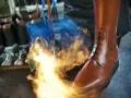 Ein brauner Reitstiefel wird mit einem Brenner bearbeitet. Werkzeuge liegen bereit für die Reitstiefel Pflege.