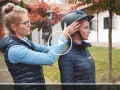 Frau passt Reiterin einen Helm an. Ein möglicher reithelm test stiftung warentest.