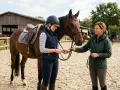 Eine Reiterin und ihre Trainerin am Pferd. Reiten ist schwer, aber mit guter Anleitung wird es leichter.