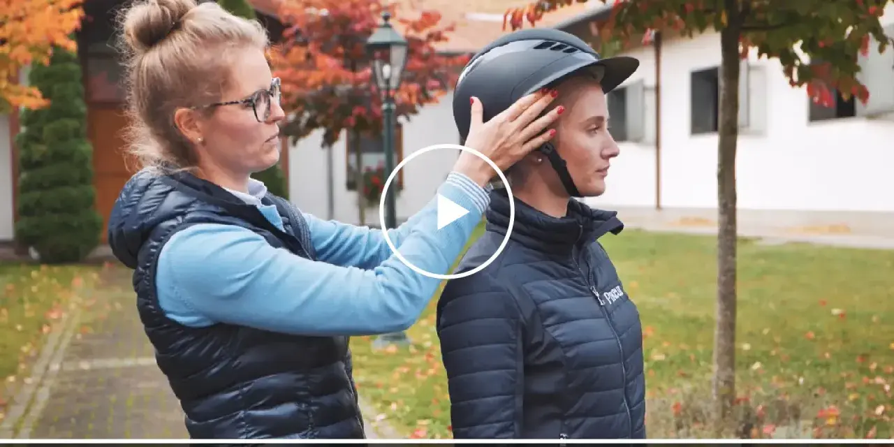 Frau passt Reiterin einen Helm an. Ein möglicher reithelm test stiftung warentest.
