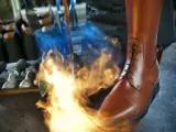 Ein brauner Reitstiefel wird mit einem Brenner bearbeitet. Werkzeuge liegen bereit für die Reitstiefel Pflege.