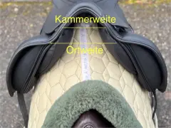 Schwarzer Sattel mit gelben Markierungen für Kammerweite und Ortweite. Ein Maßband liegt darunter.