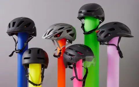 Sechs Helme, die den Unterschied zwischen Reithelm und Fahrradhelm verdeutlichen, stehen auf bunten Säulen.