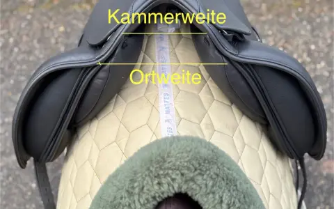 Schwarzer Sattel mit gelben Markierungen für Kammerweite und Ortweite. Ein Maßband liegt darunter.