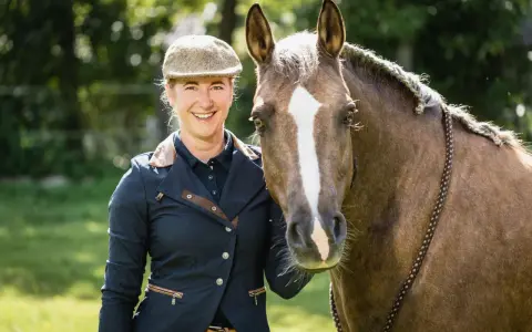 Lächelnde Reiterin mit Pferd, bereit für Working Equitation Einsteiger.