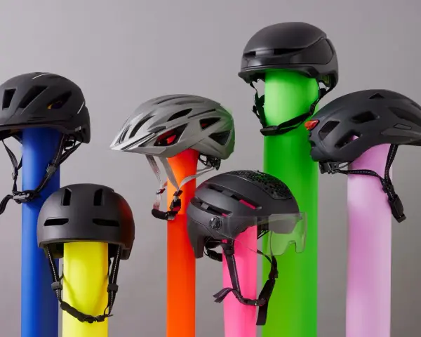 Sechs Helme, die den Unterschied zwischen Reithelm und Fahrradhelm verdeutlichen, stehen auf bunten Säulen.