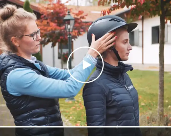 Frau passt Reiterin einen Helm an. Ein möglicher reithelm test stiftung warentest.
