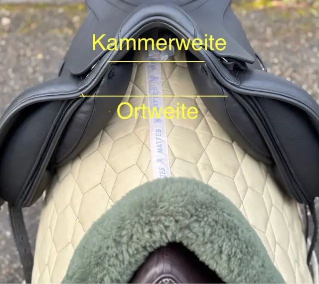 Schwarzer Sattel mit gelben Markierungen für Kammerweite und Ortweite. Ein Maßband liegt darunter.