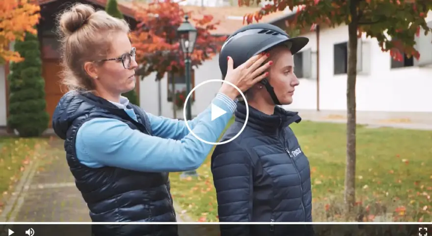 Frau passt Reiterin einen Helm an. Ein möglicher reithelm test stiftung warentest.