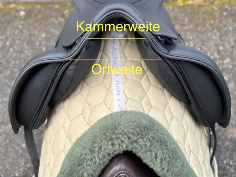 Schwarzer Sattel mit gelben Markierungen für Kammerweite und Ortweite. Ein Maßband liegt darunter.